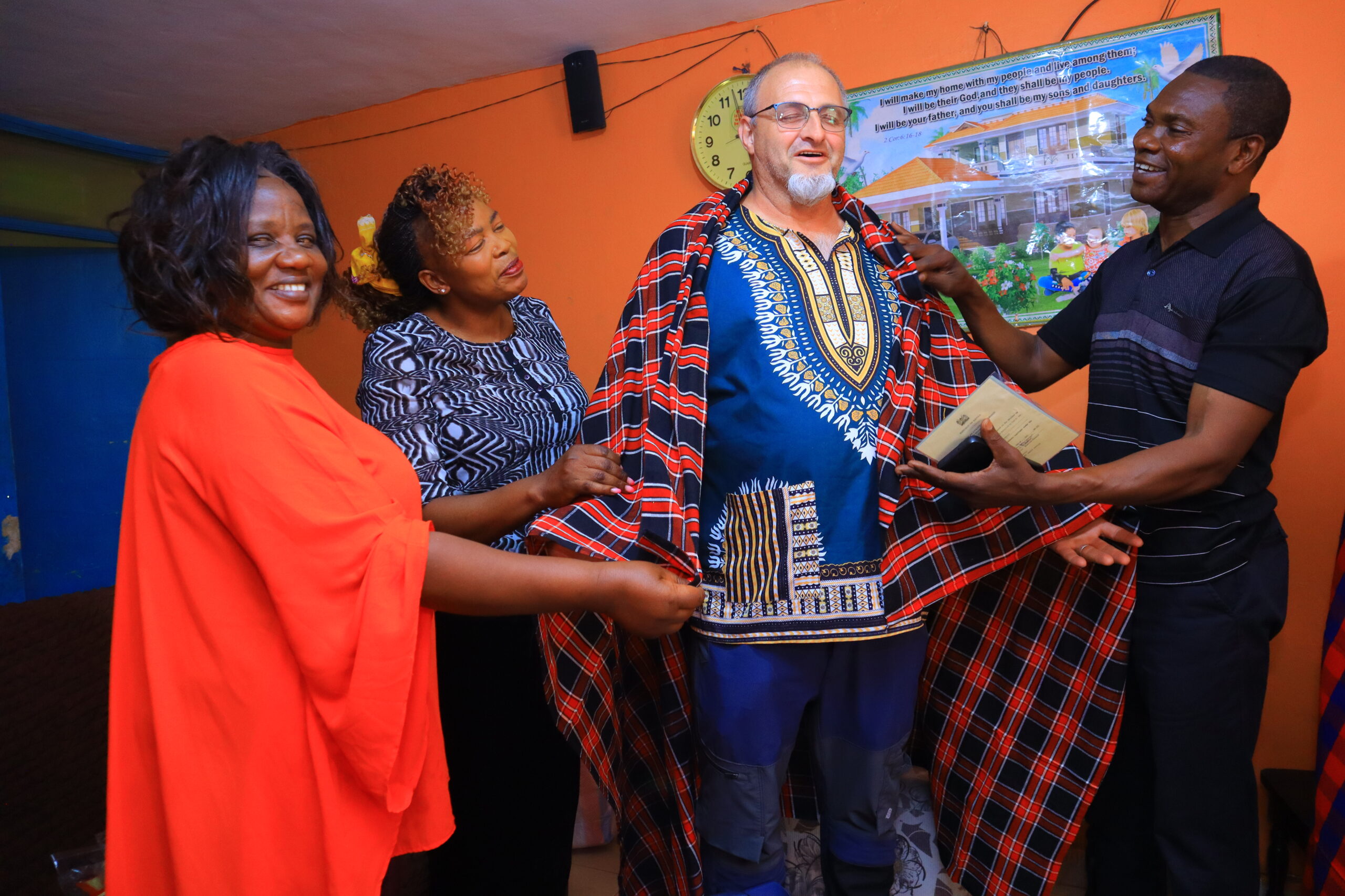 Local hosts welcoming a visitor with a traditional checked wrap in Kenya