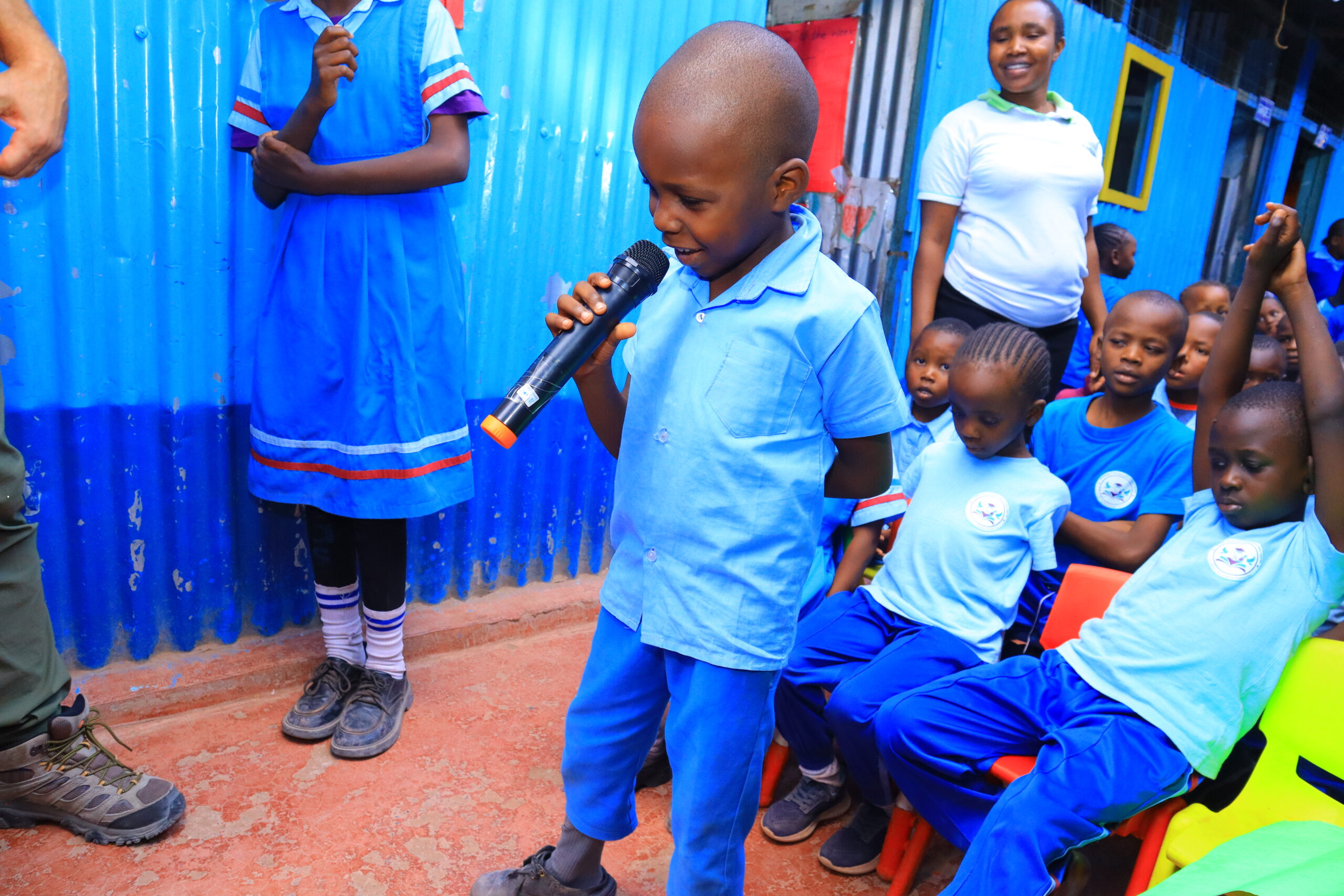 Young participant speaking into a microphone while other children listen in Kenya